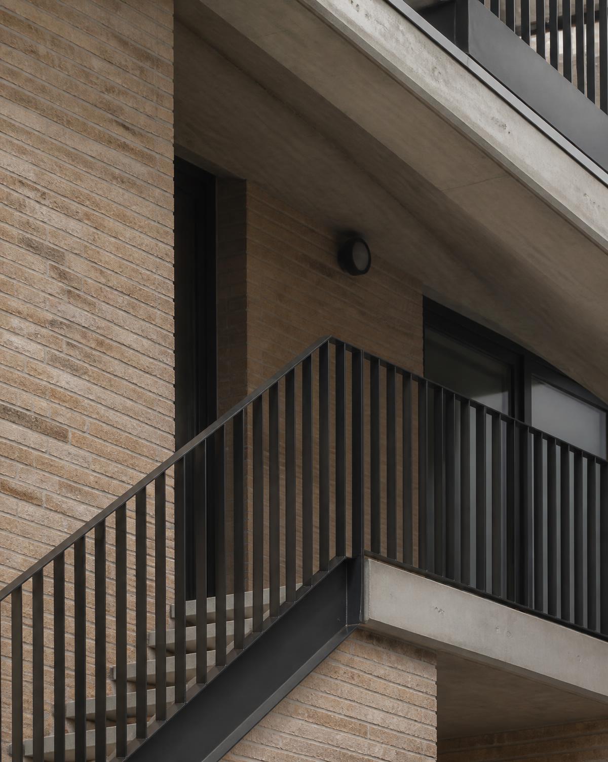 Detail of a dark metal stair balustrade against brick and concrete on a contemporary residential building